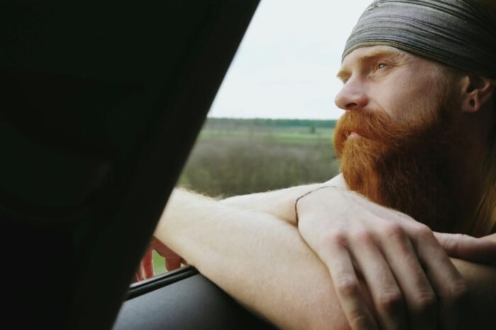 Man looking out a window in reflection while becoming more aware of his thoughts and mental patterns