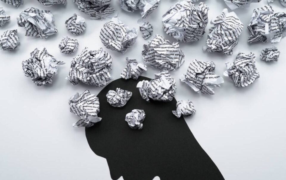 Negative self-talk image of a shadowed figured surrounded by thoughts.