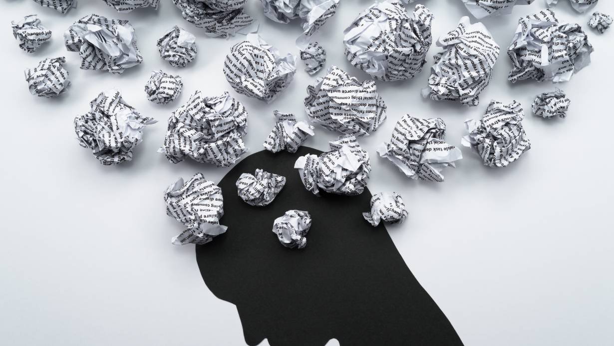 Negative self-talk image of a shadowed figured surrounded by thoughts.